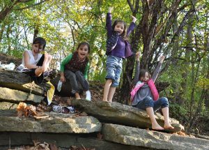 4 lachende meiden op grote stenen in het bos