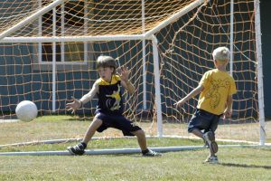 een jongen schiet een bal in het doel en de keeper kan de bal niet tegenhouden