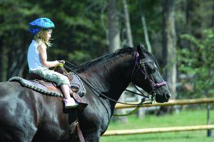 een meisje rijdt op een zwart paard