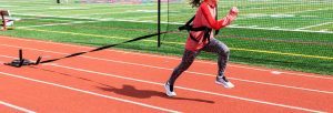 een sprinter zet kracht om vooruit te komen met een slee met gewicht achter haar