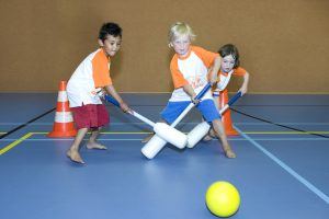 Kinderen spelen knotshockey in een gymzaal