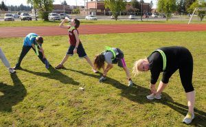 jongeren aan het strekken na het sporten aan de kant van een atletiek baan