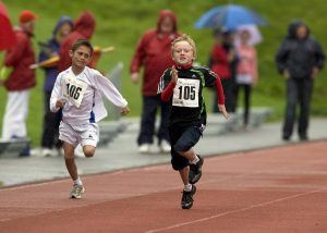 2 jongens lopen met een verbeten gezicht richting de finish op de atletiekbaan