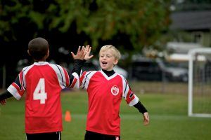 2 jongens in voetbalkleding geven elkaar een high five op het voetbalveld