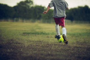 een jongen in voetbalkleding gaat tegen een voetbal trappen