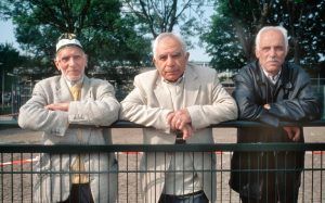 3 oudere mannen met een niet-Nederlandse achtergrond leunend op een hek