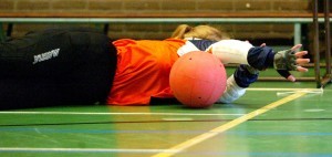 Meisje ligt op de grond van een gymzaal met een bal voor haar lichaam