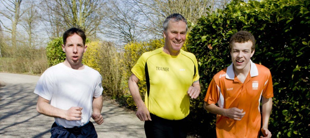 Een trainer loopt hard met 2 jongeren met een verstandelijke beperking