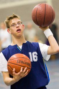 Jongen met beperking houdt 2 basketballen vast