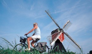 Vrouw fiets voor een molen langs