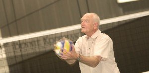 Oudere man houdt een volleybal vast bij het net