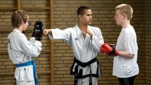 2 jongens krijgen uitleg van leraar tijdens karate les
