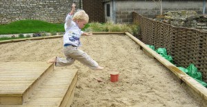 Kindje springt in het zand van een zandbak
