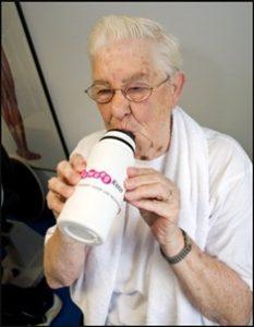 Een oudere vrouw drinkt uit een bidon