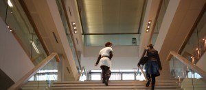 2 vrouwen lopen omhoog op een brede trap in een gebouw