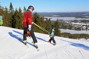 een ouder met kind op ski's boven op de piste
