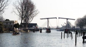 Een roeiboot met 4 roeiers gaat richting een ophaalbrug
