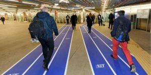Passagiers in de hal van de RET die gebruik maken van een blauw wandelpad