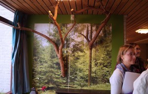 muur met fotobehang van een bos met aan de muur echte takken