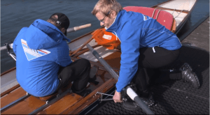 Roeier wordt in de roeiboot geholpen