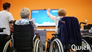 Ouderen in een rolstoel die naar een tv scherm kijken en juichen