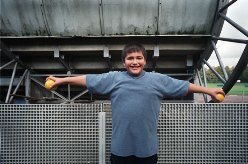 Een jongen met overgewicht houdt zijn armen opzij en omhoog en houdt in beide handen een sinaasappel vast