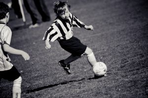 Een jongen tijdens een voetbalwedstrijd met de bal aan zijn voet