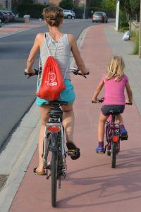 Een moeder fietst met haar kind op een fietspad