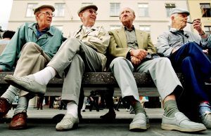 4 oudere mannen zitten buiten naast elkaar op een bankje