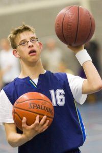 Jongere met beperking houdt 2 basketballen vast