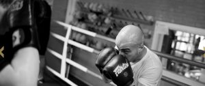 Een bokser in de ring met zijn bokshandschoenen voor zijn gezicht bij Vechtsportclub Directe