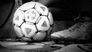 zwart-wit foto van een voetbal en een voetbalschoen