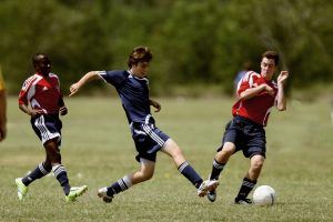 3 jonge voetballers in actie tijdens een wedstrijd