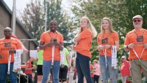 vrijwilligers in oranje shirts tijdens een sportevenement met medailles in hun handen om uit te reiken