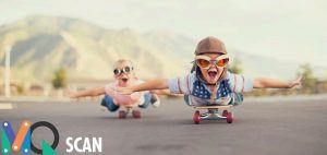 2 kindjes met grappige helm en bril liggend op een skateboard