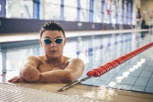 Sporter met lichamelijke beperking in het water aan de rand van een zwembad