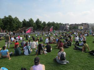 publiek van een urban sports evenement die op het gras in een park zitten te kijken
