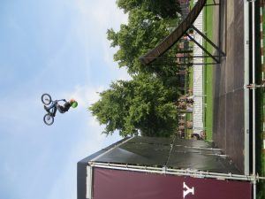 een deelnemer aan een urban sport evenement maakt hoog in de lucht een salto met zijn fiets