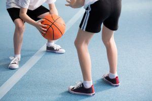 2 kinderen in een gymzaal met een basketbal