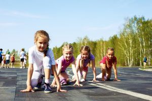 Kinderen in starthouding op een weg om te gaan sprinten