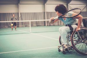 Vrouw in een rolstoel speelt tennis in een hal
