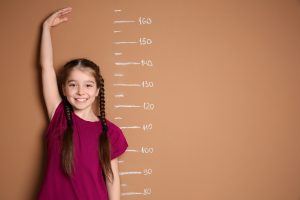 een meisje staat tegen een muur waarop een meetlat is getekend zodat ze zich kan opmeten
