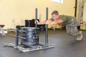 een militair duwt een sportslee met 4 zware gewichten als training