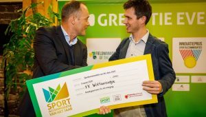 Bert van Oostveen overhandigt een cheque ter waarde van 2.000,- euro als prijs voor sportaccommodatie van het jaar