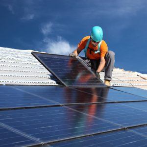 Man plaats zonnepanelen op een dak