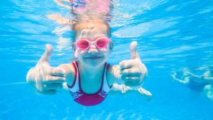 zwemmend meisje van ca. 8 jaar laat glimlachend haar thumbs up zien