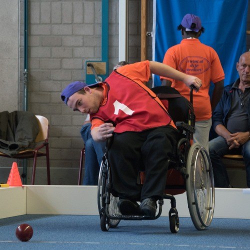 Een jonge man in een rolstoel speelt Bocce tijdens de Special Olympics