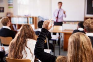 scholiere steekt hand op om vraag te stellen aan docent